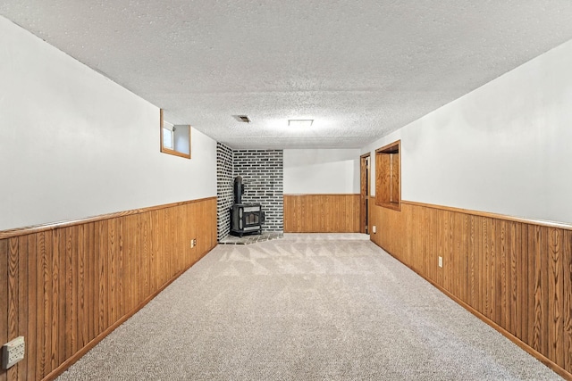 11439 Heights Dr NW, Coon Rapids, MN 55433 - unfurnished living room featuring wainscoting, wood walls, a wood stove, carpet floors, and a textured ceiling