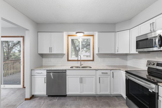11460 Goldenrod St NW, Coon Rapids, MN 55448 - kitchen with stainless steel appliances, a textured ceiling, white cabinetry, decorative backsplash, and light stone counters