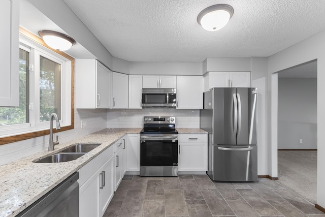 11460 Goldenrod St NW, Coon Rapids, MN 55448 - kitchen featuring appliances with stainless steel finishes, white cabinetry, a textured ceiling, decorative backsplash, and light stone countertops