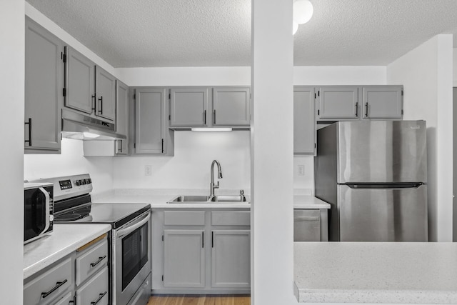 66 9th St E Unit 1712, Saint Paul, MN 55101 - kitchen featuring appliances with stainless steel finishes, under cabinet range hood, gray cabinets, a textured ceiling, and light countertops