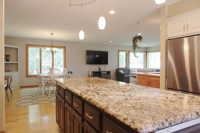 13334 Silverod Ct NW, Andover, MN 55304 - kitchen with stainless steel fridge, light wood-style flooring, healthy amount of natural light, light stone counters, and recessed lighting