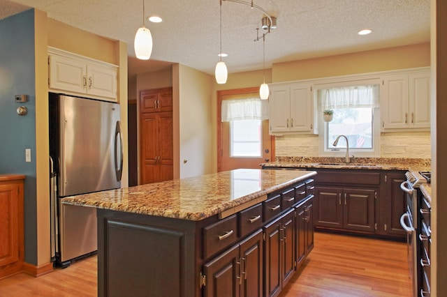 13334 Silverod Ct NW, Andover, MN 55304 - kitchen featuring stainless steel appliances, white cabinets, light wood-style flooring, dark brown cabinetry, and light stone counters