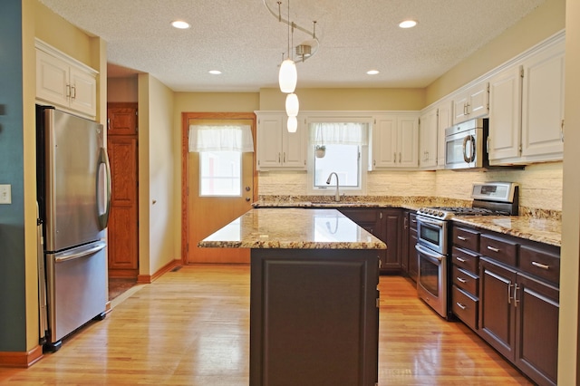 13334 Silverod Ct NW, Andover, MN 55304 - kitchen with appliances with stainless steel finishes, a center island, white cabinets, tasteful backsplash, and recessed lighting