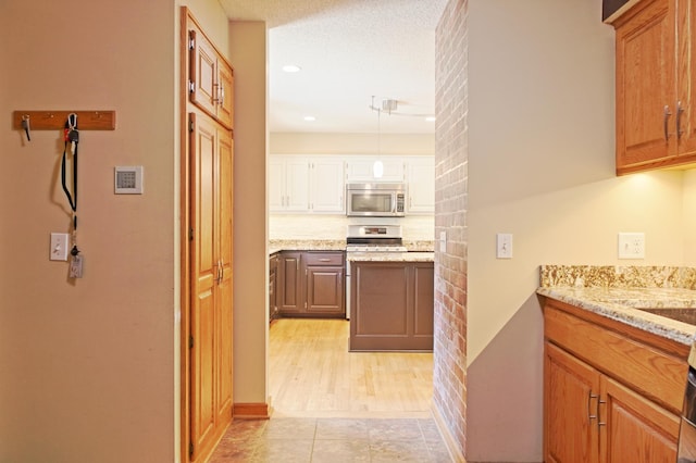 13334 Silverod Ct NW, Andover, MN 55304 - kitchen with appliances with stainless steel finishes, light stone counters, recessed lighting, white cabinetry, and hanging light fixtures