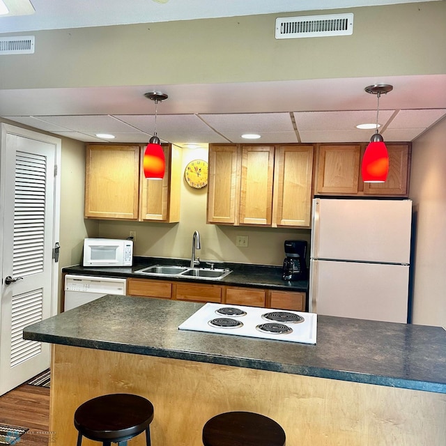 835 23rd Ave S, Moorhead, MN 56560 - kitchen with white appliances, a paneled ceiling, dark countertops, a breakfast bar, and dark wood-style floors