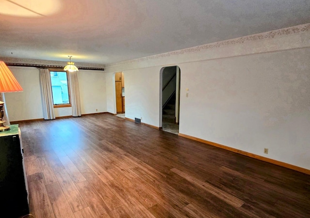 808 5th St SW, Pipestone, MN 56164 - spare room featuring arched walkways, dark wood-type flooring, and stairway
