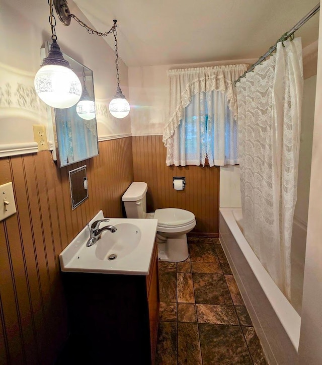 808 5th St SW, Pipestone, MN 56164 - full bathroom featuring stone finish floors, vanity, wainscoting, wood walls, and shower / bath combo with shower curtain