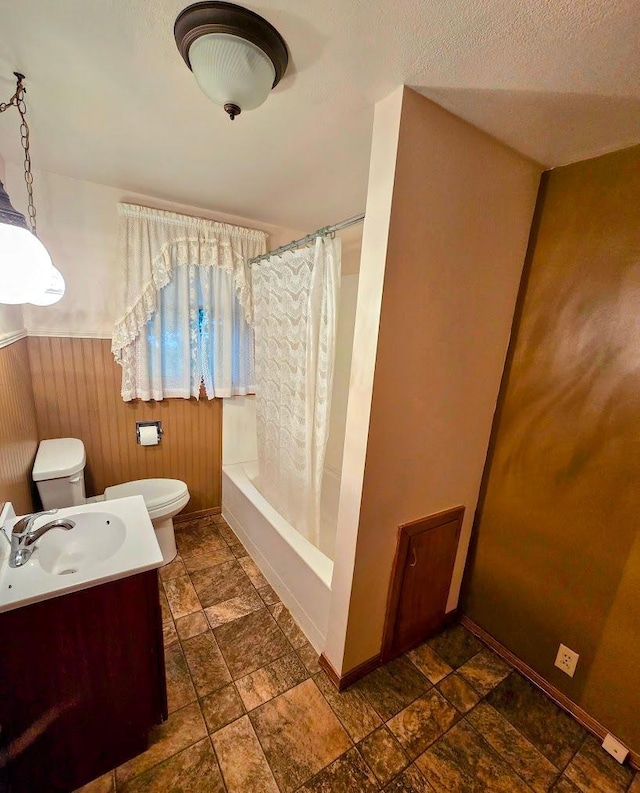 808 5th St SW, Pipestone, MN 56164 - full bathroom with stone finish flooring, vanity, shower / bath combo with shower curtain, wood walls, and wainscoting