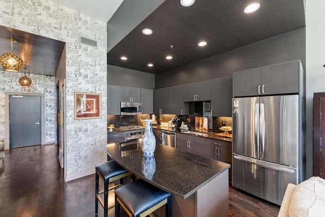 215 10th Ave S Unit 112, Minneapolis, MN 55415 - kitchen with stainless steel appliances, wallpapered walls, dark wood finished floors, a kitchen breakfast bar, and gray cabinets