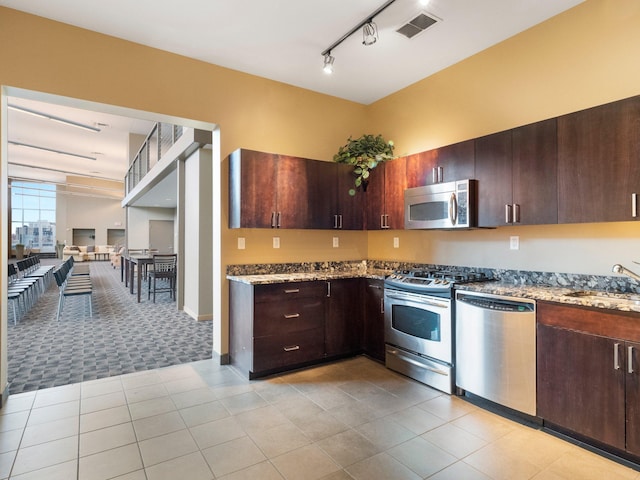 215 10th Ave S Unit 112, Minneapolis, MN 55415 - kitchen with stainless steel appliances, light stone counters, track lighting, and dark brown cabinetry