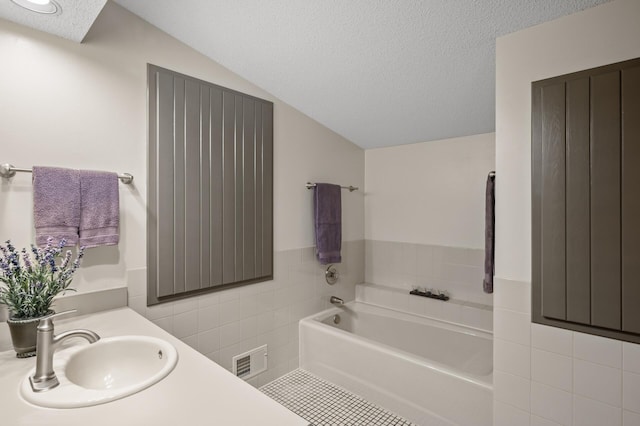 11409 Bren Rd, Minnetonka, MN 55343 - bathroom featuring tile walls, a garden tub, vanity, and a textured ceiling
