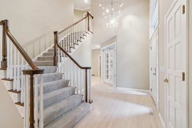 7005 Valley View Rd, Edina, MN 55439 - entryway featuring stairs, light wood-type flooring, a towering ceiling, a chandelier, and crown molding