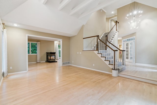 7005 Valley View Rd, Edina, MN 55439 - unfurnished living room featuring wood finished floors, stairway, high vaulted ceiling, a chandelier, and french doors