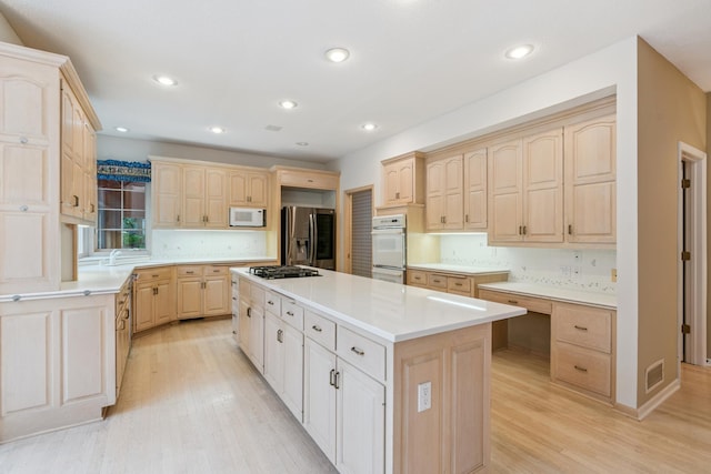 7005 Valley View Rd, Edina, MN 55439 - kitchen featuring appliances with stainless steel finishes, light brown cabinets, a kitchen island, light wood-type flooring, and light countertops