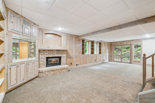 7005 Valley View Rd, Edina, MN 55439 - unfurnished living room featuring wooden walls, carpet flooring, a fireplace, and a drop ceiling