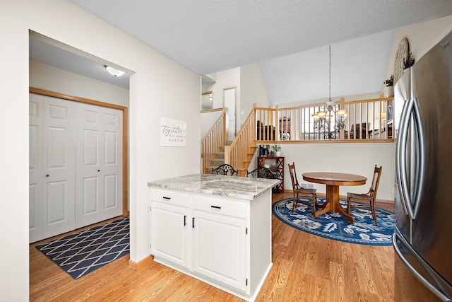16391 Adret Ct, Eden Prairie, MN 55346 - kitchen with freestanding refrigerator, a chandelier, light wood-type flooring, white cabinets, and a peninsula