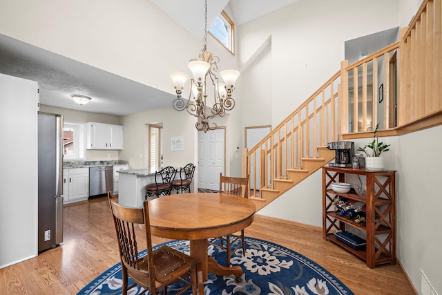 16391 Adret Ct, Eden Prairie, MN 55346 - dining room featuring healthy amount of natural light, light wood-style flooring, a chandelier, stairway, and a towering ceiling