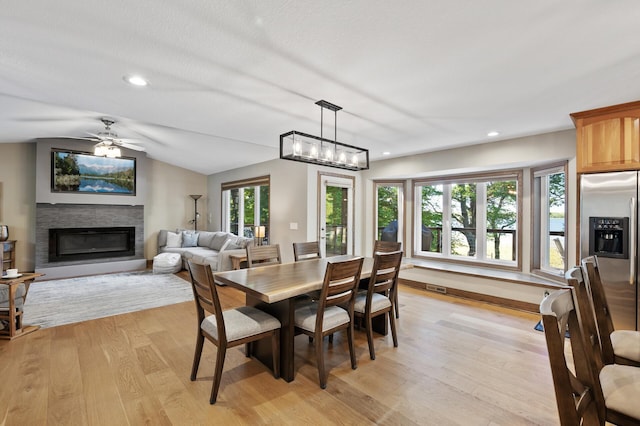 27858 Nathan Ln, Chisago Lake Twp, MN 55045 - dining room with a glass covered fireplace, light wood finished floors, recessed lighting, vaulted ceiling, and ceiling fan