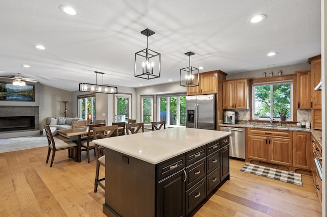 27858 Nathan Ln, Chisago Lake Twp, MN 55045 - kitchen with appliances with stainless steel finishes, a breakfast bar area, a glass covered fireplace, a kitchen island, and light wood finished floors