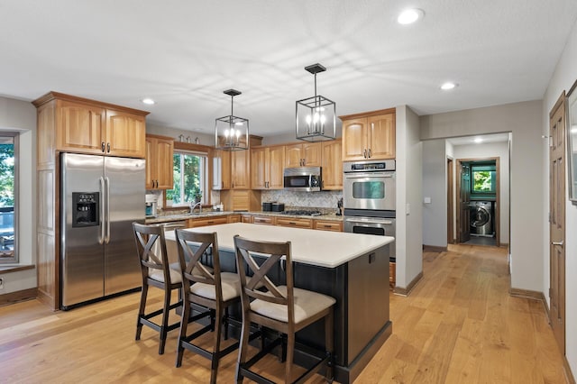 27858 Nathan Ln, Chisago Lake Twp, MN 55045 - kitchen with appliances with stainless steel finishes, washer / dryer, backsplash, light countertops, and a kitchen island