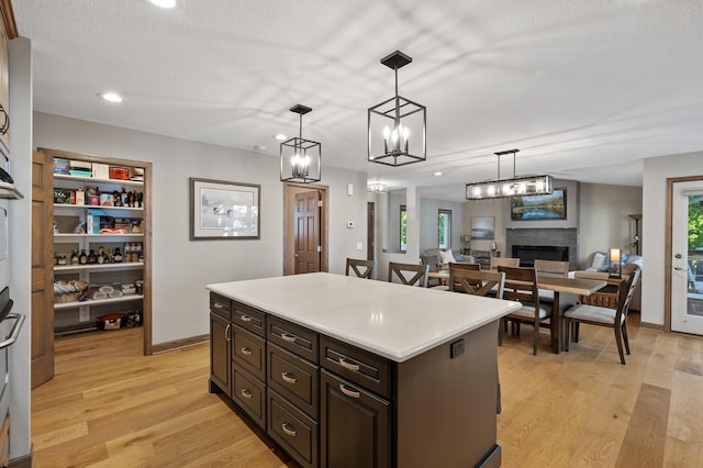 27858 Nathan Ln, Chisago Lake Twp, MN 55045 - kitchen with decorative light fixtures, light countertops, a fireplace, light wood-style flooring, and a center island
