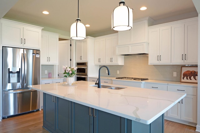 5120 Coronado Dr, Woodbury, MN 55129 - kitchen with appliances with stainless steel finishes, white cabinetry, light wood finished floors, an island with sink, and decorative backsplash