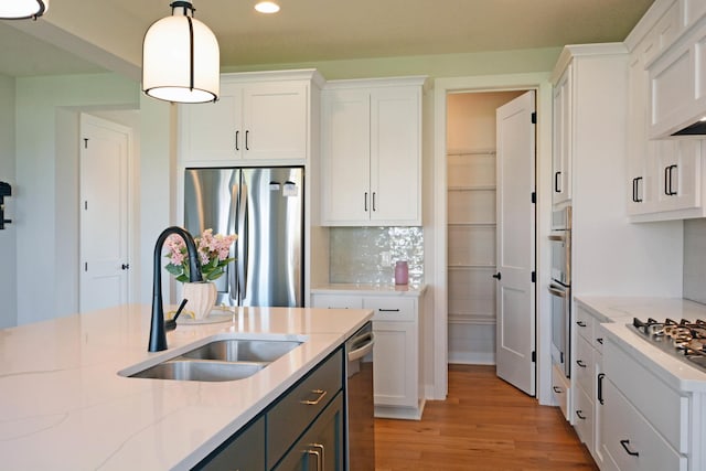 5120 Coronado Dr, Woodbury, MN 55129 - kitchen featuring appliances with stainless steel finishes, white cabinets, recessed lighting, light wood-type flooring, and pendant lighting