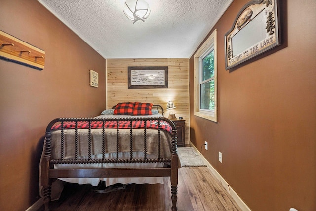 38985 337th Ln, Aitkin, MN 56431 - bedroom featuring wooden walls, wood finished floors, a textured ceiling, and an accent wall