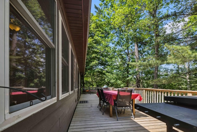 38985 337th Ln, Aitkin, MN 56431 - wooden terrace with outdoor dining area and view of wooded area