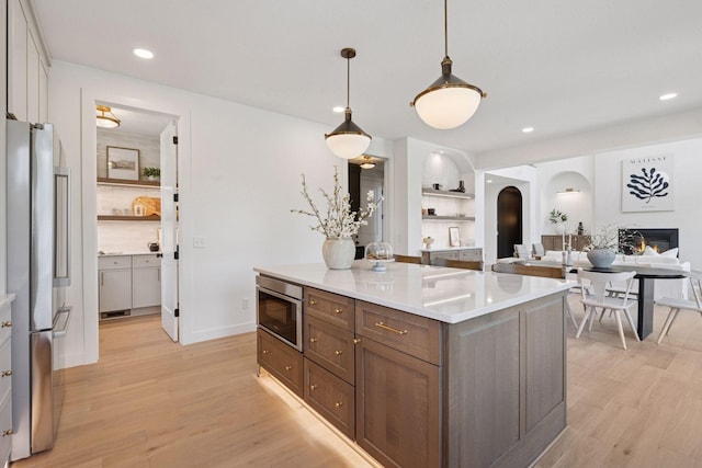 4404 58th St, Edina, MN 55424 - kitchen featuring freestanding refrigerator, arched walkways, light wood-style flooring, light countertops, and hanging light fixtures