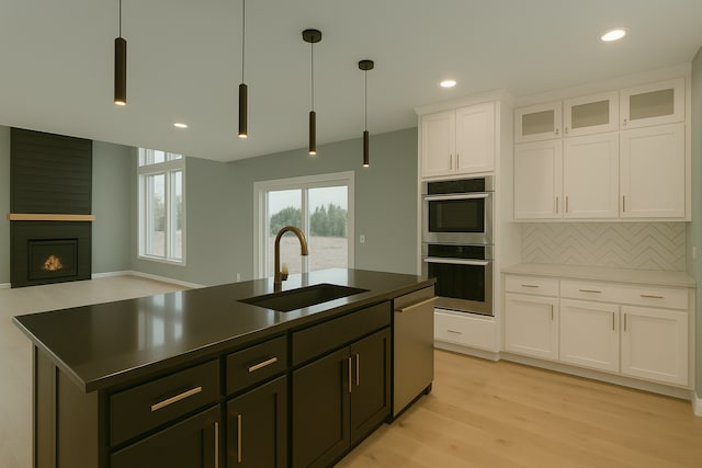 917 174th Ave NE, Ham Lake, MN 55304 - kitchen with stainless steel appliances, backsplash, white cabinetry, light wood-type flooring, and a center island with sink