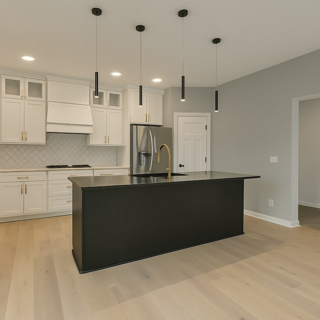 917 174th Ave NE, Ham Lake, MN 55304 - kitchen featuring light wood-style floors, custom range hood, stainless steel fridge with ice dispenser, a center island with sink, and cooktop