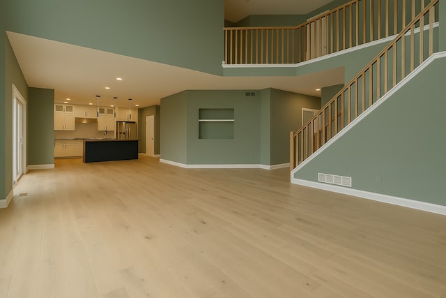 917 174th Ave NE, Ham Lake, MN 55304 - unfurnished living room featuring a towering ceiling, light wood-style floors, recessed lighting, and stairway
