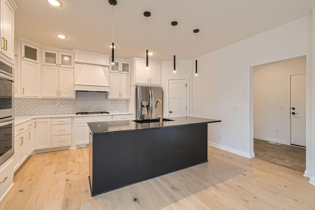 917 174th Ave NE, Ham Lake, MN 55304 - kitchen with custom exhaust hood, backsplash, stainless steel appliances, an island with sink, and light wood finished floors