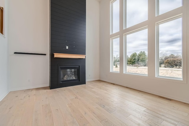 917 174th Ave NE, Ham Lake, MN 55304 - unfurnished living room with hardwood / wood-style flooring, a large fireplace, and a towering ceiling