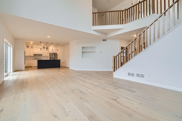 917 174th Ave NE, Ham Lake, MN 55304 - unfurnished living room with light wood-style floors, stairs, a towering ceiling, and recessed lighting
