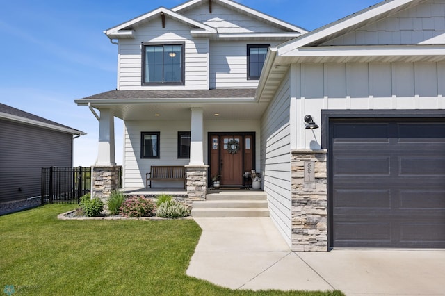 8871 Cottonwood Blvd, Horace, ND 58047 - view of front of home featuring a porch, stone siding, a front lawn, a garage, and board and batten siding