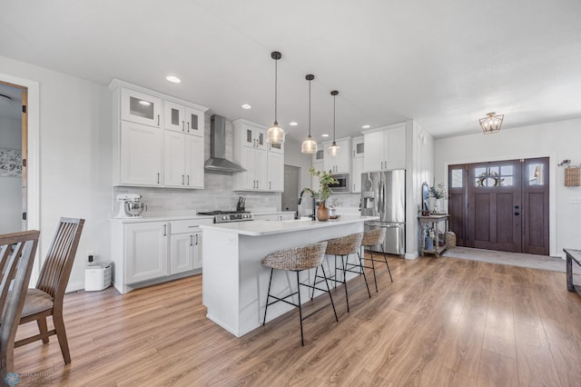 8871 Cottonwood Blvd, Horace, ND 58047 - kitchen featuring appliances with stainless steel finishes, wall chimney range hood, light wood-type flooring, a breakfast bar, and light countertops