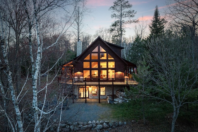 15193 Wilderness Trl, Crosslake, MN 56442 - back of property featuring a chimney, stone siding, a wooden deck, and a patio area