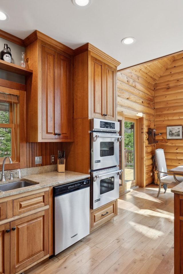 15193 Wilderness Trl, Crosslake, MN 56442 - kitchen with appliances with stainless steel finishes, log walls, light wood-type flooring, brown cabinetry, and lofted ceiling