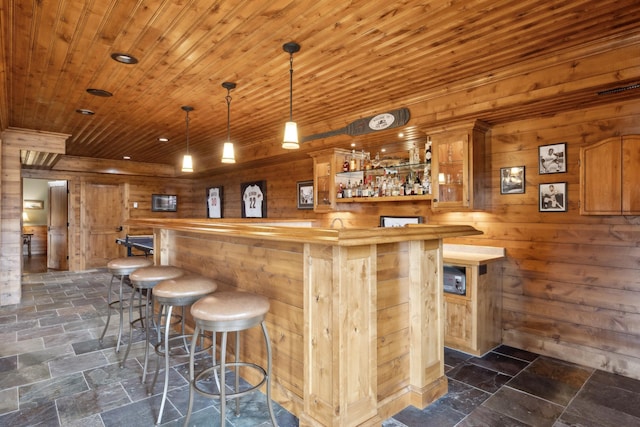 15193 Wilderness Trl, Crosslake, MN 56442 - indoor dry bar with wooden walls, stone tile floors, wooden ceiling, and decorative light fixtures