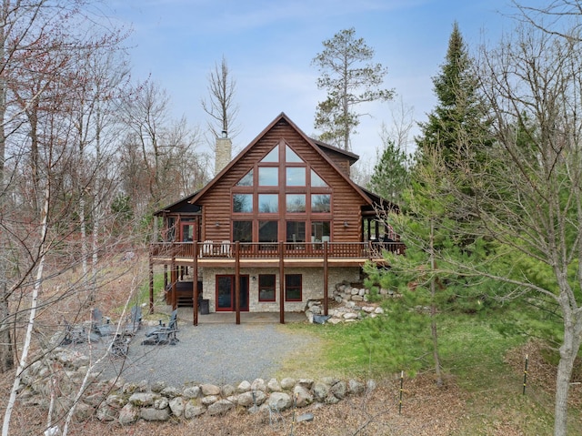 15193 Wilderness Trl, Crosslake, MN 56442 - back of house with stone siding, log exterior, a deck, a patio, and a chimney