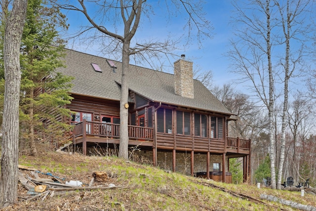 15193 Wilderness Trl, Crosslake, MN 56442 - back of property featuring a sunroom, a shingled roof, a chimney, and a deck