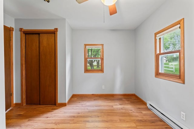 202 Cedar St, Pepin, WI 54759 - unfurnished bedroom featuring a baseboard heating unit, multiple windows, light wood finished floors, and a ceiling fan