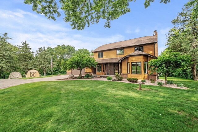 9950 204th Street Ct N, Forest Lake, MN 55025 - view of front of home with driveway, a front lawn, a shed, a chimney, and covered porch