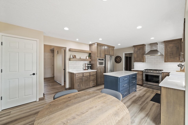 9950 204th Street Ct N, Forest Lake, MN 55025 - kitchen featuring wall chimney exhaust hood, appliances with stainless steel finishes, open shelves, tasteful backsplash, and light wood-type flooring