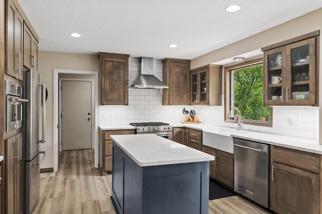 9950 204th Street Ct N, Forest Lake, MN 55025 - kitchen with wall chimney range hood, stainless steel appliances, light wood finished floors, a kitchen island, and glass insert cabinets