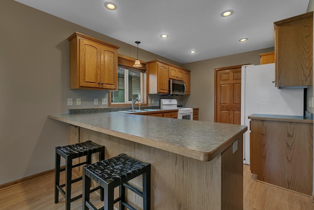 1664 Payton Ct NE, Sauk Rapids, MN 56379 - kitchen featuring white appliances, light wood finished floors, a kitchen breakfast bar, a peninsula, and recessed lighting