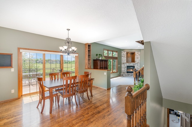 517 Redpoll Ave SE, New Prague, MN 56071 - dining space featuring light wood-type flooring, a chandelier, and a brick fireplace