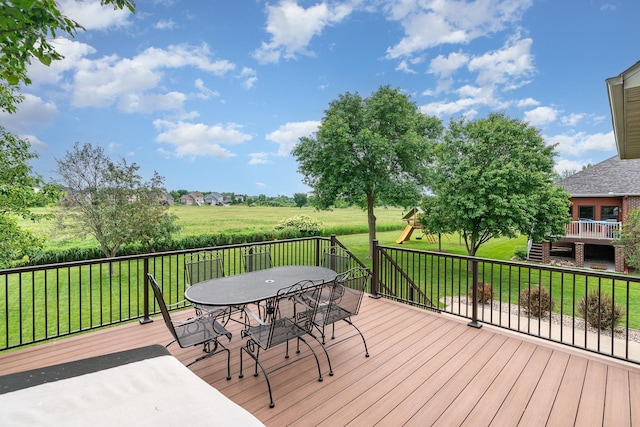 517 Redpoll Ave SE, New Prague, MN 56071 - wooden terrace with outdoor dining area, a yard, and a playground